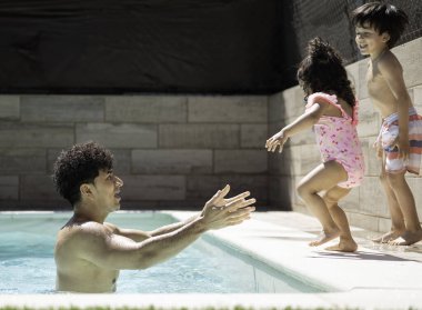 Latin babası, kızının güneşli bir yaz gününde havuza atladığını görmek için bekliyor.