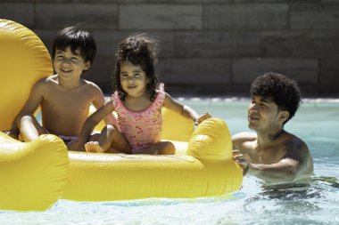 Latin baba şişme ördek itiyor mutlu çocukları yüzme havuzunda taşıyor