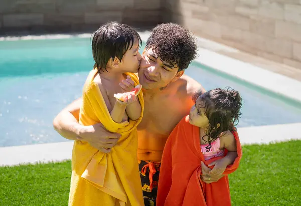 Havuza sarılıp karpuz yiyen mutlu Latin aile portresi.