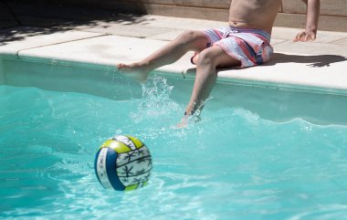Çocuk oyun oynarken ve ayakları şişme top ile yüzme havuzunda su sıçratırken yakın plan.