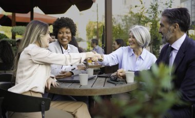 Açık bir kafede yapılan bir toplantıda çeşitli iş adamları el sıkışıyor.