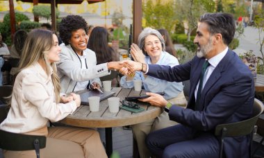 İş ortakları, açık bir kafede yapılan bir toplantıda anlaşmaya vardıktan sonra el sıkışıyor.