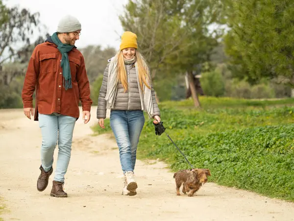 Gülümseyen genç bir çift parkta köpeklerini gezdiriyorlar. Kış günü fotokopi çektikleri yerde rahatça geziniyorlar.