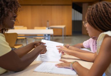 Belgeye işaret eden Afrikalı Amerikalı öğretmen, okuldaki genç öğrencilere
