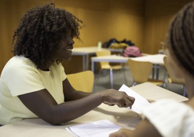 Gülümseyen Afrikalı kadın öğretmen sınıftaki genç öğrencilere dersi anlatıyor.