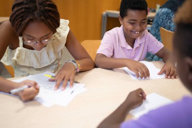 Eğitimsel bir faaliyet sırasında görevler üzerinde işbirliği yapan Afro genç öğrenciler