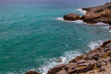Kayalara çarpan dalgalar, İspanya 'da zümrüt berrak su