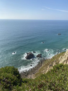 Portekiz kayalıklarından nefes kesici Atlantik Okyanusu manzarası. Zümrüt sular kayalık çıkıntıları sarıyor. Bereketli kıyı bitkileri dramatik deniz manzarası çerçeveleri.