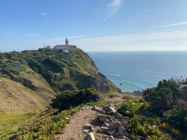 Rocky yürüyüş yolu dramatik Portekiz uçurumundaki Cabo da Roca deniz fenerine çıkıyor. Taş yol Atlantik Okyanusu 'na bakan kıyı bitkilerinden geçiyor..