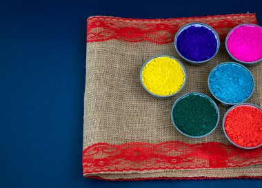 Koyu arkaplanda çok renkli holi boyası olan renkli holi tozunun üst görüntüsü. Mutlu Holi festivali dekorasyonu.