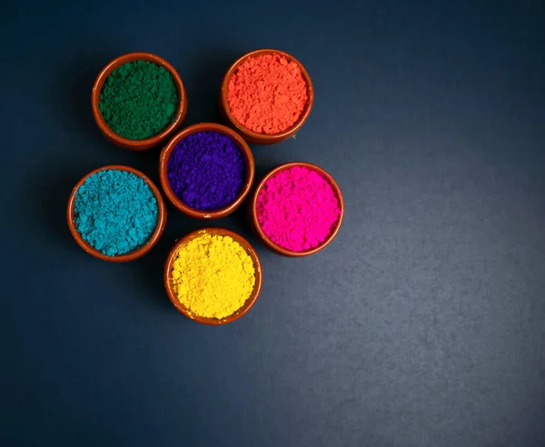 top view of colorful traditional holi powder in bowls isolated on dark background.Space for text . happy holi.Concept Indian color festival called Holi