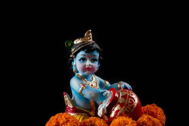 Hindu tanrısı Krishna. Siyah arkaplanda çiçekli heykel