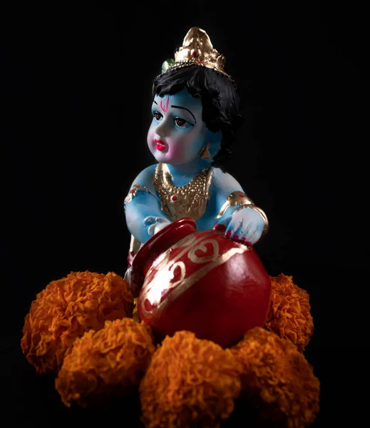 印度教神克里希纳黑色背景的印度达喜手风琴节上有花朵的雕像 — 图库照片