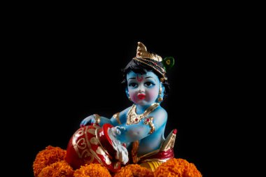 Hindu tanrısı Krishna. Siyah arkaplanda çiçekli heykel