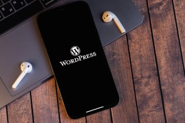 WordPress logo mobil uygulaması ekrandaki akıllı telefon iPhone 'unda defter, hava kapsülleri kulaklıkları. WordPress - açık kaynak içerik yönetim sistemi. Batum, Gürcistan - 5 Ekim 2022