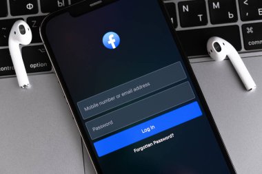 Akıllı telefon iPhone ve AirPods 'da Facebook mobil uygulaması, MacBook yakın plan. Facebook dünyadaki en büyük ve en popüler sosyal ağ sitesidir. Batum, Gürcistan - 3 Mart 2023