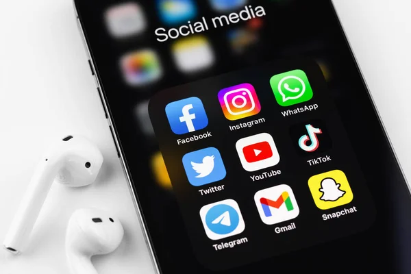 stock image showing social media apps icons of Facebook, Instagram, WhatsApp, Twitter, Youtube, TikTok, Telegram, Gmail, Snapchat - on screen smartphone iPhone with AirPods closeup. Batumi, Georgia - August 9, 2022