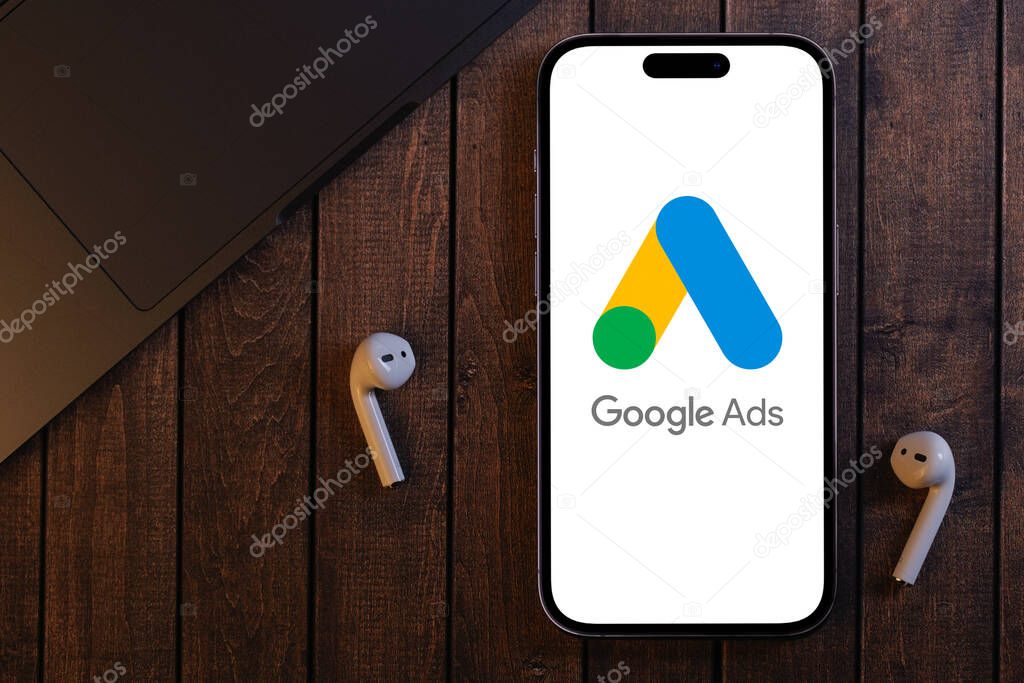 Google Ads logo mobile app on the screen smartphone iPhone with notebook, airpods headphones. Ads is a service of contextual, basically, search advertising from Google. Batumi, Georgia - October 6, 2022
