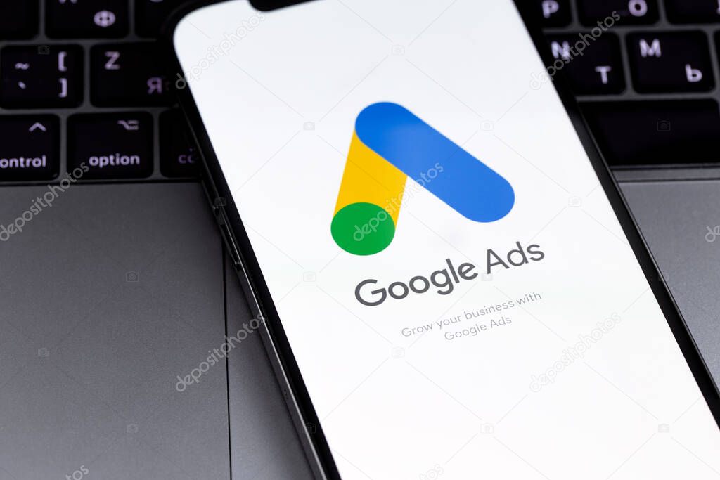 Google Ads logo mobile app on the screen smartphone iPhone with MacBook closeup. Ads is a service of contextual, basically, search advertising from Google. Batumi, Georgia - March 2, 2023