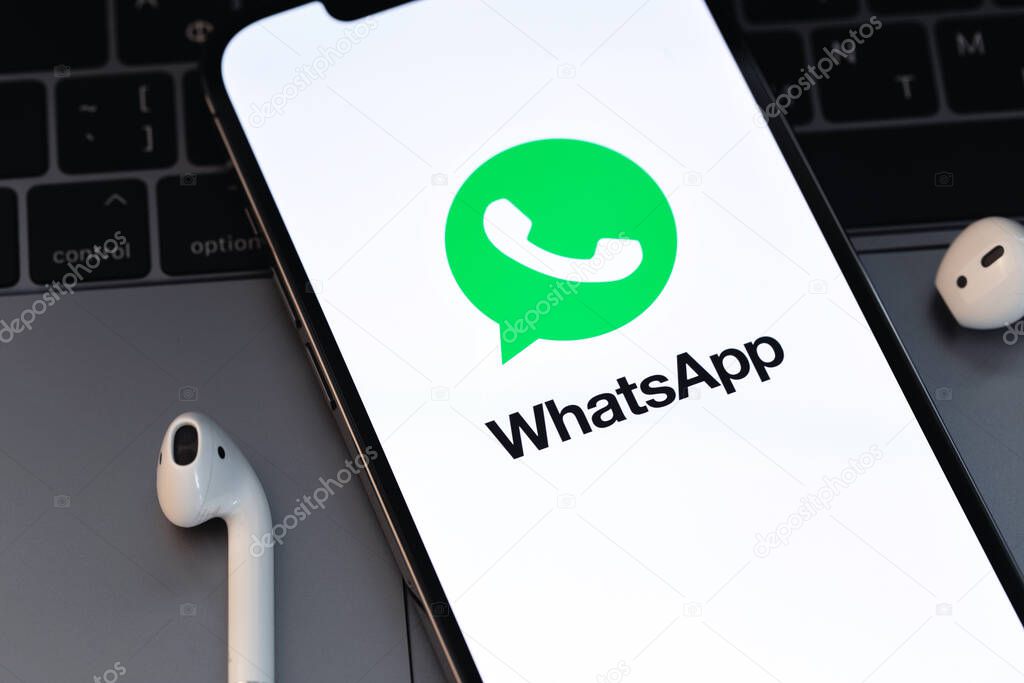 WhatsApp logo mobile app on the screen smartphone iPhone with AirPods closeup. WhatsApp is a popular free instant text messaging system for mobile and other platforms. Batumi, Georgia - March 3, 202