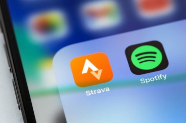 Strava ve Spotify mobil uygulamaları ekrandaki akıllı telefon iPhone 'unda. Strava, mobil cihazlar kullanarak atletlerin faaliyetlerini takip eden bir hizmettir. Batum, Gürcistan - 12 Nisan 2023