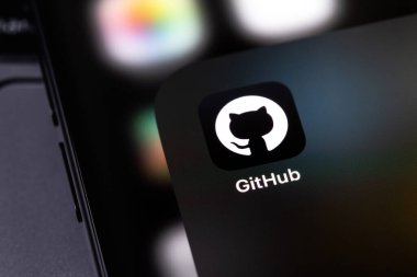 GitHub mobil simge uygulaması bir ekranda akıllı telefon ve defter kapanışı. GitHub, bilişim projelerine ev sahipliği yapmak ve geliştirmek için en büyük web hizmetidir. Batum, Gürcistan - 4 Kasım 2023