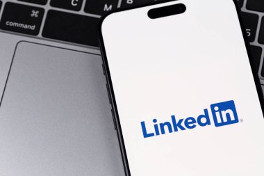 Macbook arkaplanlı akıllı telefondan logo mobil uygulaması bağlandı. LinkedIn, iş bağlantılarını bulmak ve kurmak için kullanılan bir sosyal ağ. Batum, Gürcistan - 28 Ekim 2023