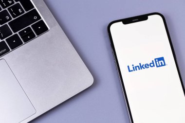 Bilgisayarlı akıllı telefon iPhone 'una logo mobil uygulaması bağlandı. LinkedIn, iş bağlantılarını bulmak ve kurmak için kullanılan bir sosyal ağ. Batum, Gürcistan - 12 Ekim 2023