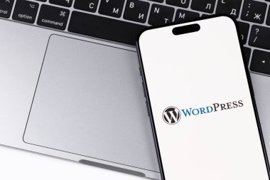 WordPress logo mobil uygulaması Macbook arka planına sahip bir akıllı telefon iPhone ekranında. WordPress - açık kaynak içerik yönetim sistemi. Batum, Gürcistan - 28 Ekim 2023