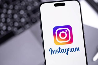 Bulanık iş yeri arka planında bir ekrandaki akıllı telefon iPhone üzerinde Instagram logo mobil uygulaması. Instagram akıllı telefonlar için fotoğraf paylaşım uygulamasıdır. Batumi, Gürcistan - 7 Kasım 2023 
