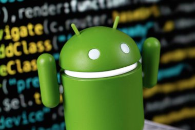 Google Android figürü yakın plan ve dijital programlama kodu arka planı. Google Android akıllı telefonlar, tablet bilgisayarlar ve diğer cihazlar için bir işletim sistemidir. Batum, Gürcistan - 20 Aralık 2023