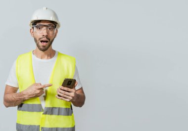 Cep telefonunu kullanan ve işaret eden bir mühendis. Cep telefonu kullanan ve işaret eden inanılmaz bir inşaat işçisi. Cep telefonu kullanmasına şaşırdım. İnşaat mühendisi telefon reklamını işaret ediyor.