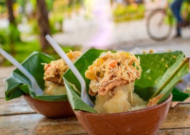 Granada, Nikaragua 'nın tipik yiyeceği. Geleneksel muz yapraklı Vigoron ahşap bir masada servis edilir. Nikaragua gıda konsepti, tahta bir masada servis edilen iki enerjiye yakın çekim.