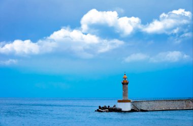 İskelenin kıyısında bir deniz feneri, mavi gökyüzü ile çevrili bir deniz feneri.