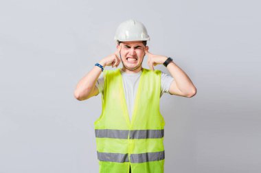 Kulaklarını kapatan genç mühendis, kulak ağrısı olan inşaatçı, kulaklarını acı ifadesiyle kapatan mühendis, kulak ağrısı olan mühendis, izole edilmiş mühendis.