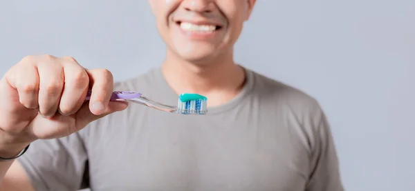 Young man showing toothbrush with toothpaste isolated, guy holding brush with toothpaste on white background, Person showing a toothbrush with toothpaste