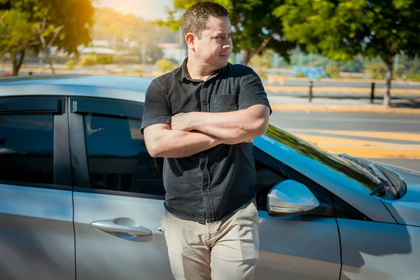 Man with crossed arms leaning on the car. Young man with arms crossed leaning on his new car. People leaning on car with arms crossed with copy space