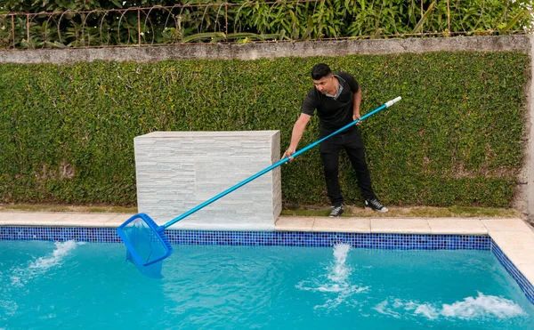 Swimming pool cleaning and maintenance concept. Maintenance person cleaning a swimming pool with skimmer, Worker cleaning a swimming pool with skimmer