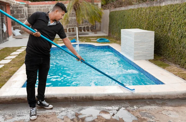 Swimming pool cleaning with brush. Maintenance person cleaning swimming pool with brush, Worker cleaning a swimming pool with special brush
