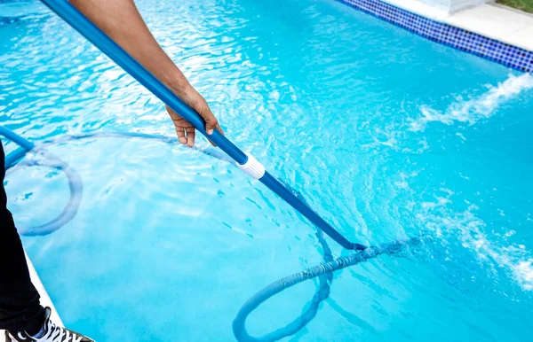Pool maintenance and cleaning with vacuum hose. People cleaning swimming pool with suction hose. Close-up of man cleaning a swimming pool with a vacuum hose