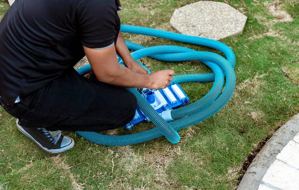 Man connecting the handle on the pool vacuum. Suction equipment connection for swimming pool, Pool suction hose installation. Person connecting pool hose handle