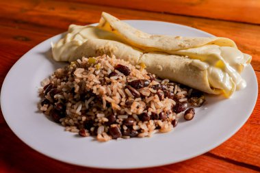 Traditional gallo pinto with Quesillo served on wooden table. Nicaraguan gallopinto with quesillo on the table. typical nicaraguan foods clipart