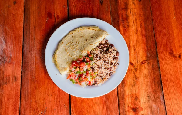 Gallo Pinto ve Pico de Gallo tabakları ahşap masada. Nikaragua yemekleri Gallo pinto ile pico de gallo ve Quesillo servis edilir.