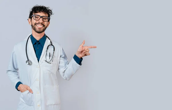 若い医者は彼の指で昇進を指している 広告スペースを指すハンサムな医者隔離された 幸せな医師指す右とともに指 — ストック写真