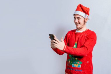 Cep telefonuna gülümseyen, Noel şapkalı mutlu adam. Noel Baba şapkalı insanlar izole edilmiş cep telefonlarını kullanıyor ve gülümsüyor Noel şapkalı genç adam izole edilmiş cep telefonlarını kullanıyor.