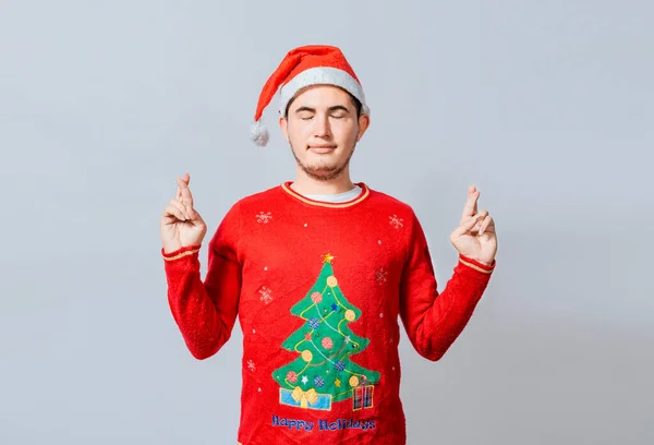 Hopeful man in christmas clothes making a wish, Handsome man in christmas hat making a wish on white background, Guy with christmas hat making a wish on isolated background