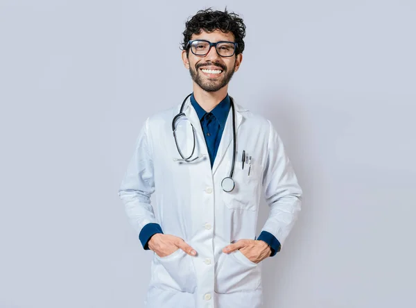 在孤立的背景下微笑的医生 快乐的医生手插在口袋里面带微笑的年轻医生被隔离的画像 — 图库照片