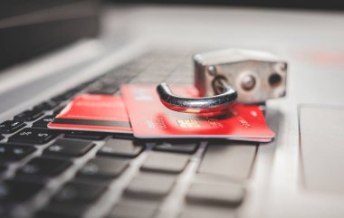 Kredi kartlarında bilgi hırsızlığı kavramı. Laptop klavyesindeki kredi kartının üstünde asma kilit, klavyede kredi kartıyla asma kilit