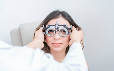 Göz doktoru, optometrist deneme aşamasındaki hastayı muayene ediyor. Doktor optometrist deneme çerçeveli hastanın görüşünü ayarlıyor