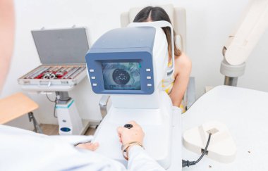Optometrist hastada refraktometre kullanıyor. Refraktometre ekranında bir hastanın görme duyusu.